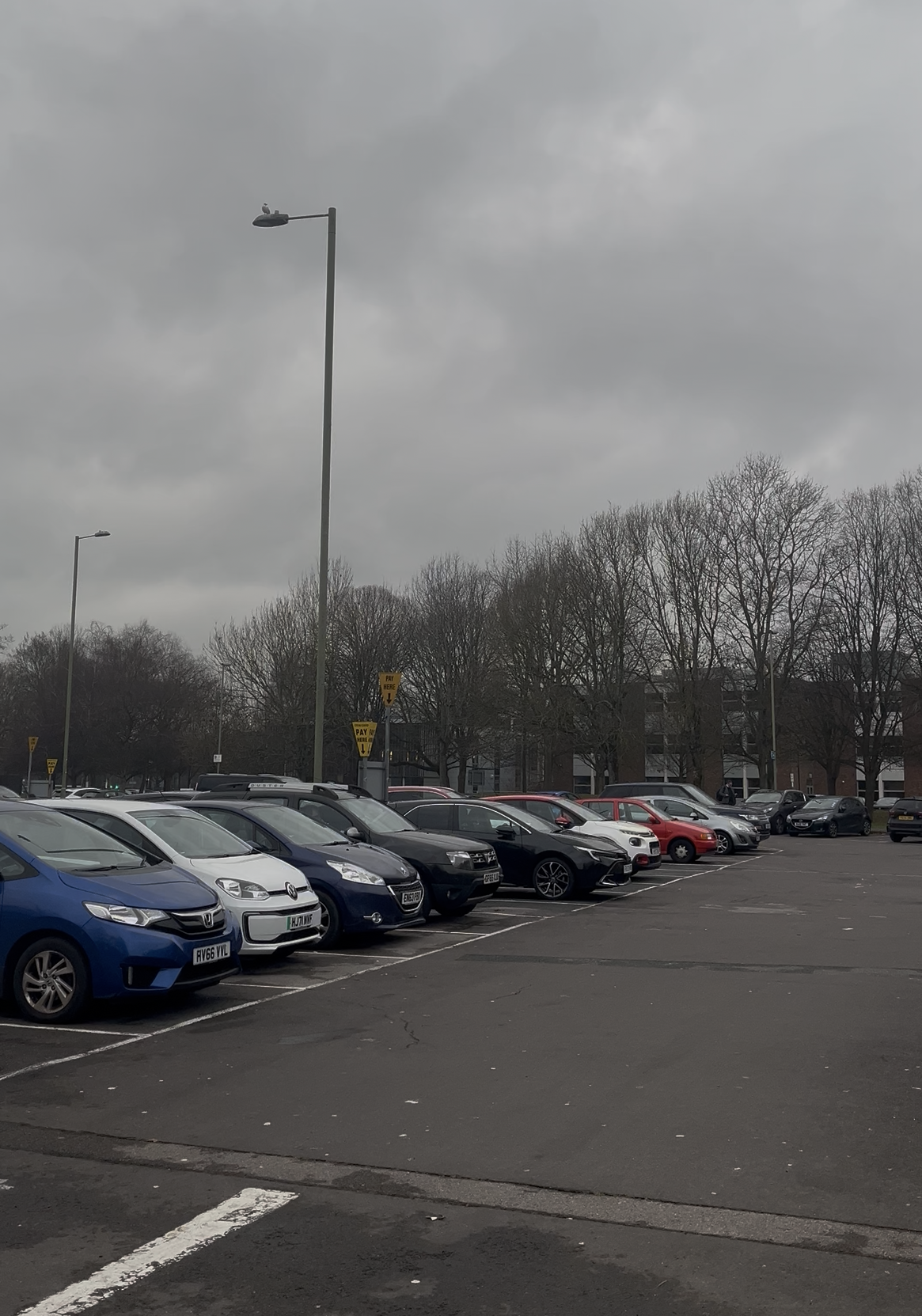 Cars parked under a cloudy sky.
